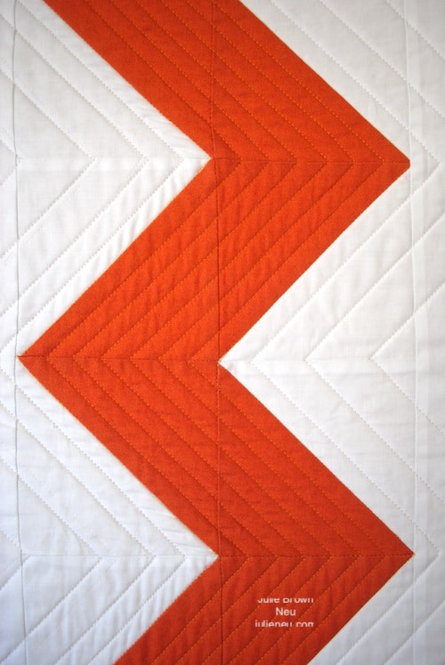 detail of quilt with orange zigzag on white background