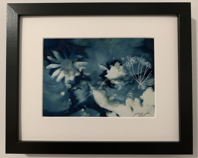 cyanotype of white daisy like flowers on blue background, with white mat and black frame