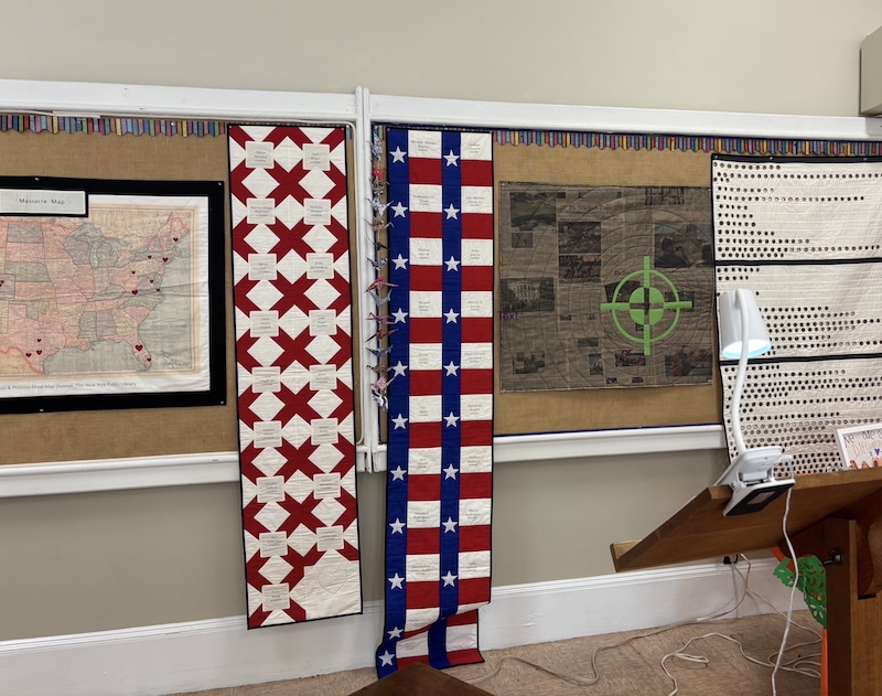 quilts hanging on bulletin board behind lectern